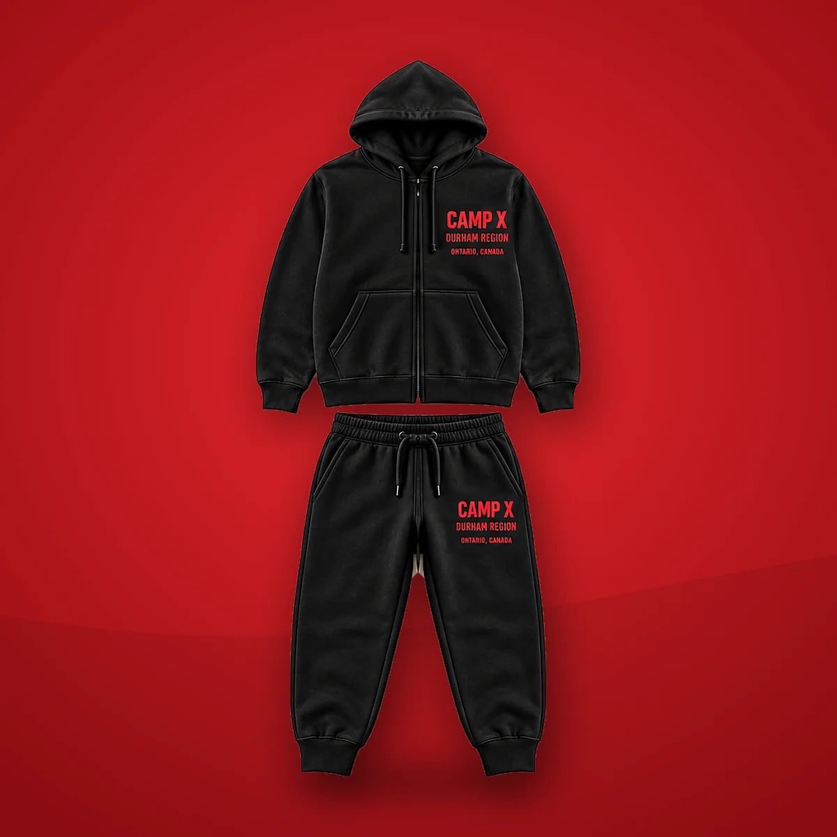 Camp X Durham Region Red Print Cotton Tracksuit: black zip-up hoodie and joggers with red CAMP X Durham Region print on a red background